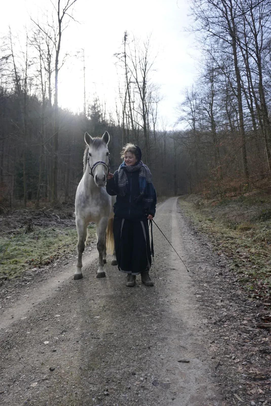 Fiete und ihr Schimmel gehen nebeneinander einen Waldweg entlang